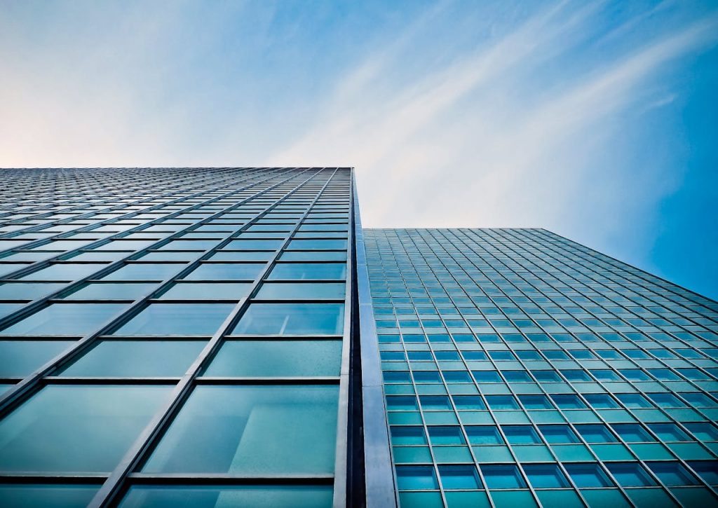 A low angle view of a modern glass skyscraper against a clear blue sky.